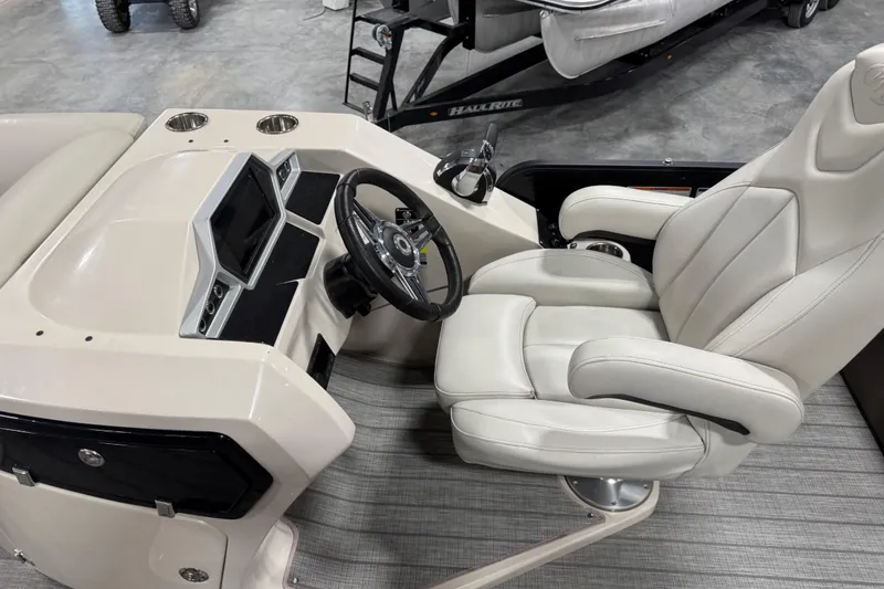 Slide: The Image of 2021 Manitou 23 Oasis boat interior with steering wheel and plush captain's chair. - 12