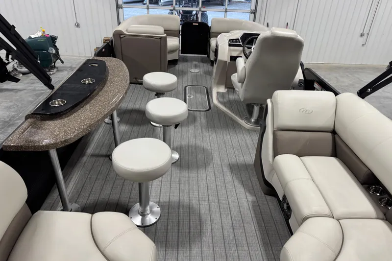 Slide: The Image of 2021 Manitou 23 Oasis boat interior with plush seating and bar stools. - 14