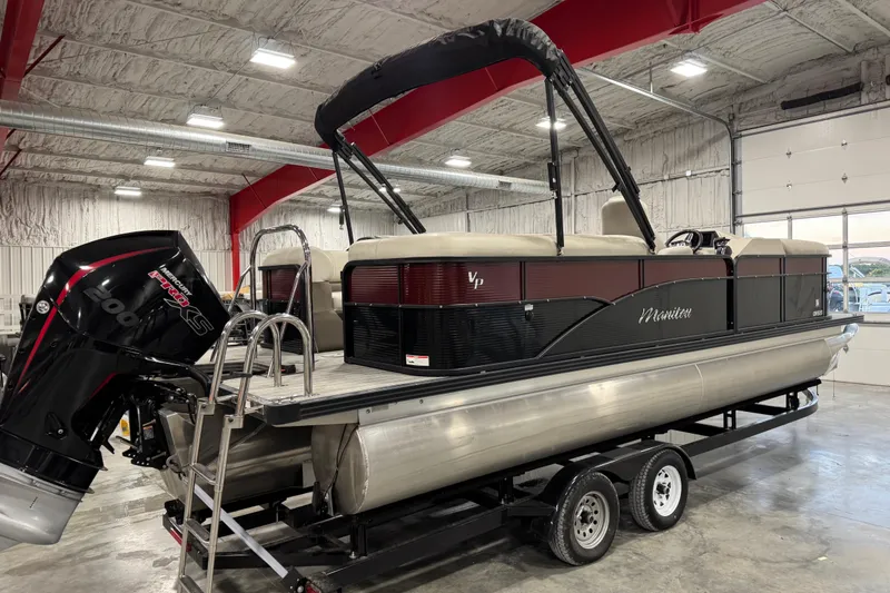 Slide: The Image of 2021 Manitou 23 Oasis pontoon boat in a garage, featuring a powerful outboard motor. - 4