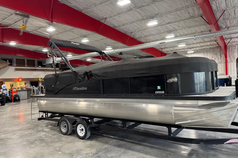 Slide: The Image of 2021 Manitou 23 Oasis pontoon boat in a showroom, covered and on a trailer. - 7
