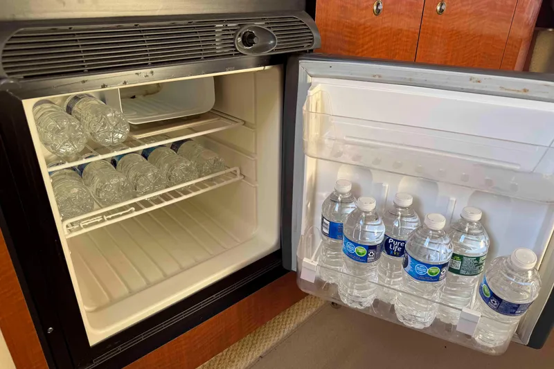 Slide: The Image of Mini fridge stocked with water bottles on a 2002 Sea Ray 320 Sundancer boat. - 21