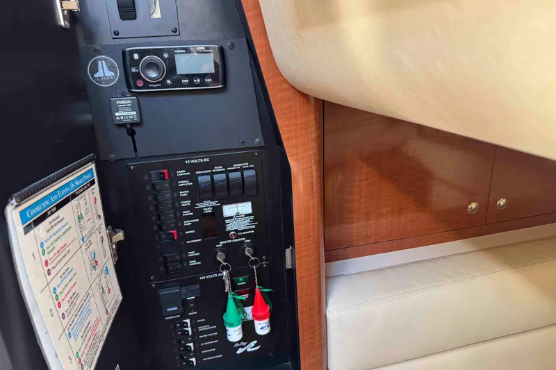 Slide: The Image of Control panel inside 2002 Sea Ray 320 Sundancer boat, featuring electrical switches and audio system. - 23