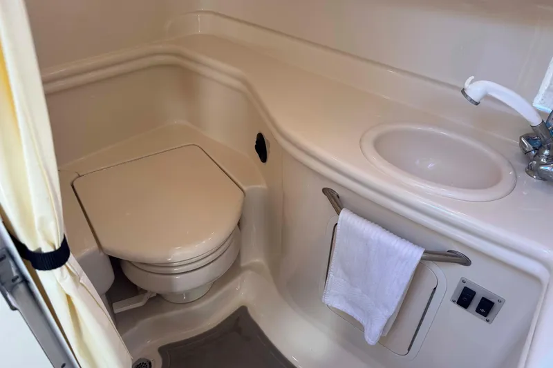 Slide: The Image of 2002 Sea Ray 320 Sundancer bathroom with toilet, sink, and towel rack. - 24