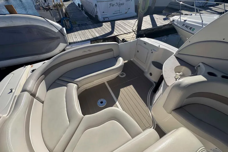 Slide: The Image of 2002 Sea Ray 320 Sundancer boat interior with beige seating and dock view. - 8