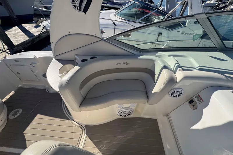 Slide: The Image of 2002 Sea Ray 320 Sundancer boat interior with cushioned seating and cup holders. - 9