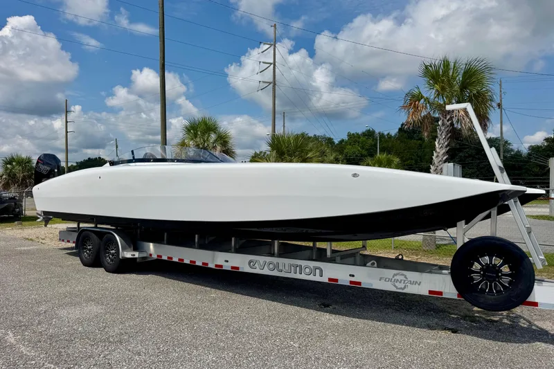 Slide: The Image of 2024 Fountain 34 Thundercat boat on trailer, parked outdoors under a blue sky. - 3