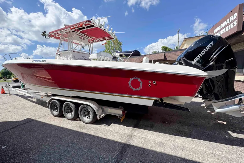 The Image of 2008 Fountain 38 Tournament Edition boat with red hull on trailer, featuring Mercury engines. - 0