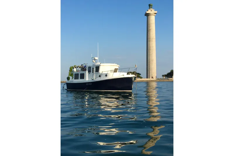Slide: The Image of 2005 American Tug 34 Pilothouse boat on calm water near a tall monument. - 11