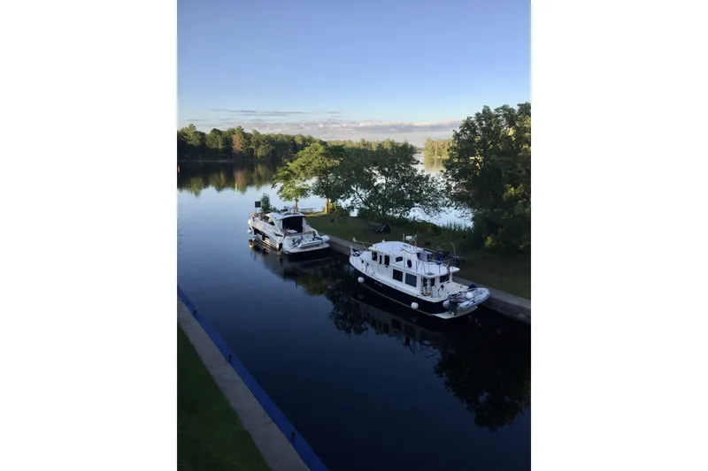 Slide: The Image of Boats docked on a serene river, featuring a 2005 American Tug 34 Pilothouse. - 118