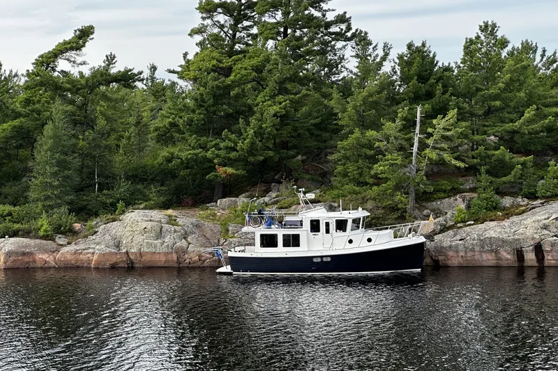 Slide: The Image of 2005 American Tug 34 Pilothouse moored by rocky forested shoreline. - 120