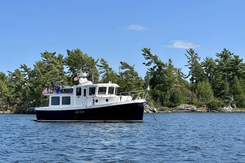 Slide: The Image of 2005 American Tug 34 Pilothouse on serene lake with lush forest backdrop. - 125