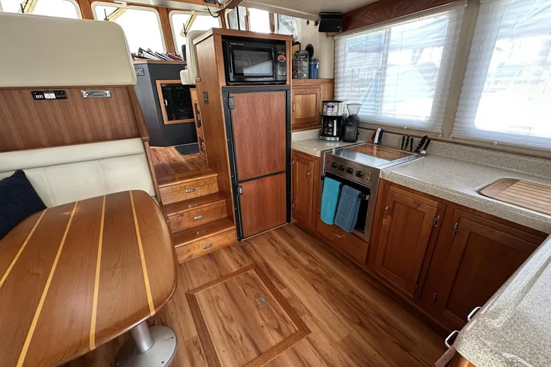 Slide: The Image of 2005 American Tug 34 Pilothouse interior with wood finish, kitchenette, and dining area. - 14