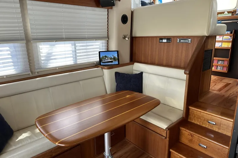 Slide: The Image of Interior of 2005 American Tug 34 Pilothouse with wooden table and seating area. - 17