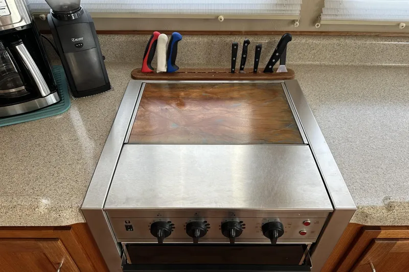 Slide: The Image of 2005 American Tug 34 Pilothouse kitchen with stove, knives, and coffee maker on countertop. - 21
