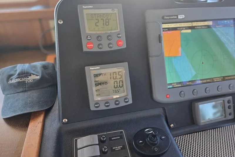 Slide: The Image of American Tug 34 Pilothouse 2005 dashboard with navigation instruments and branded cap. - 48