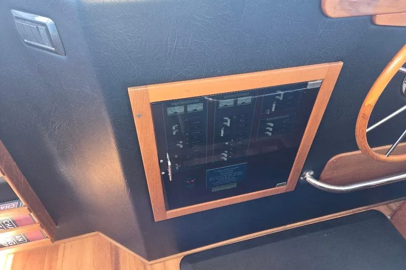 Slide: The Image of 2005 American Tug 34 Pilothouse electrical panel with wooden trim and steering wheel. - 57