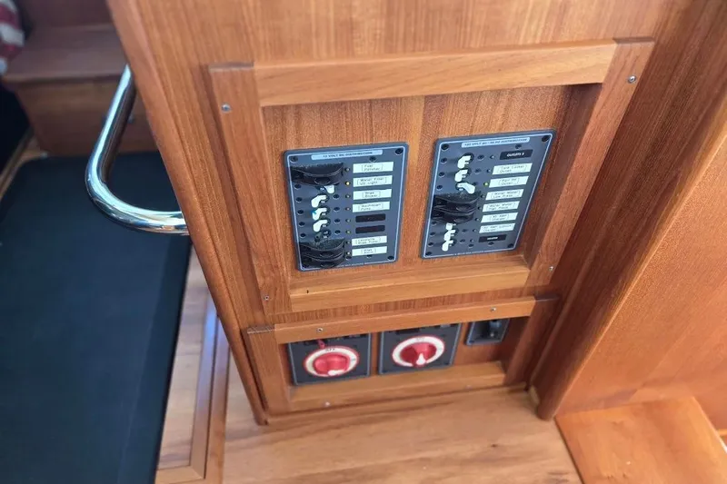 Slide: The Image of Electrical panel in 2005 American Tug 34 Pilothouse, featuring wooden finish and control switches. - 59
