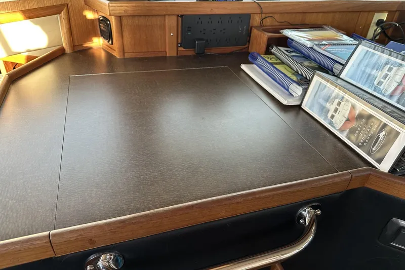 Slide: The Image of Pilothouse interior of 2005 American Tug 34, featuring a desk and organized manuals. - 61