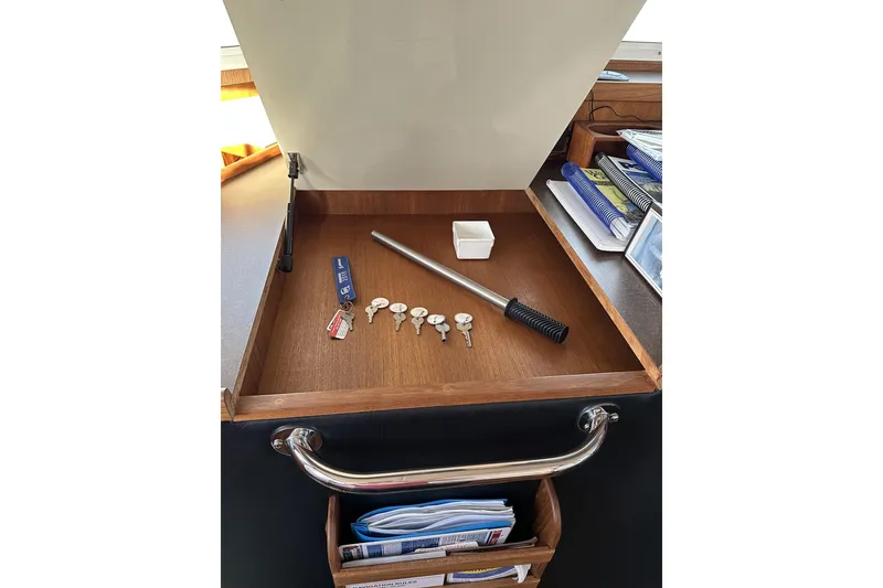 Slide: The Image of Open storage compartment in 2005 American Tug 34 Pilothouse with keys and documents. - 62