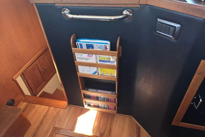 Slide: The Image of 2005 American Tug 34 Pilothouse interior with wooden magazine rack and nautical charts. - 64