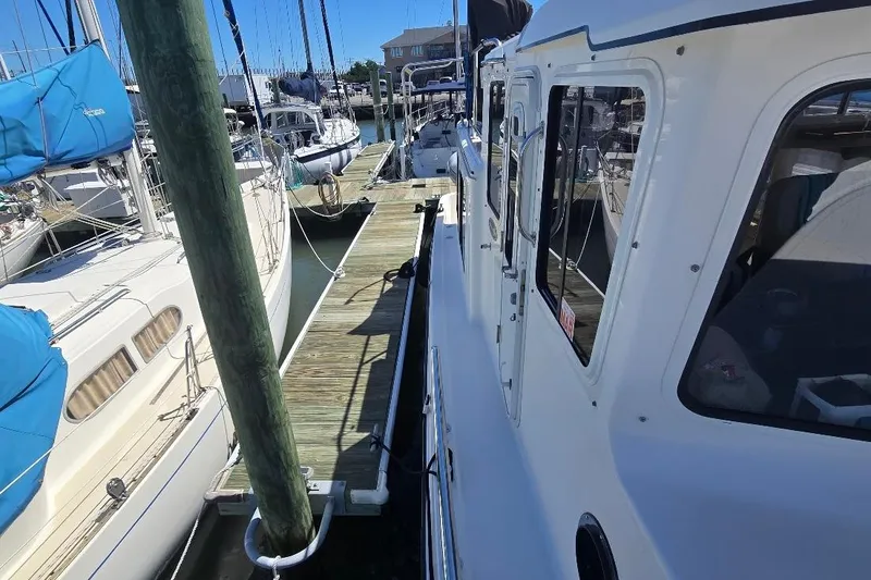 Slide: The Image of 2005 American Tug 34 Pilothouse docked at marina, surrounded by sailboats. - 89