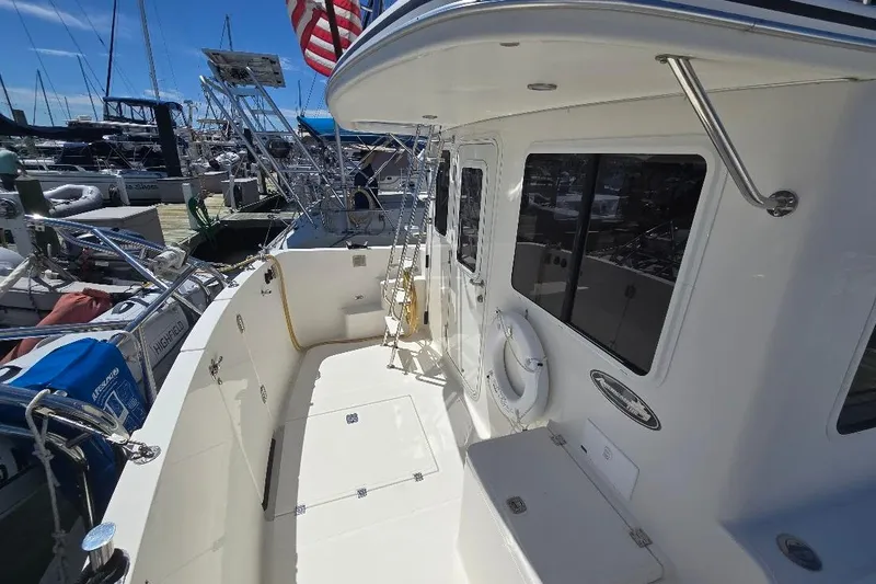 Slide: The Image of 2005 American Tug 34 Pilothouse boat docked, featuring spacious deck and safety equipment. - 90