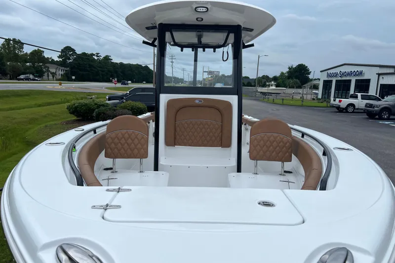 Slide: The Image of 2026 Sea Hunt Ultra 255 SE boat with tan seating, displayed outdoors near a showroom. - 8