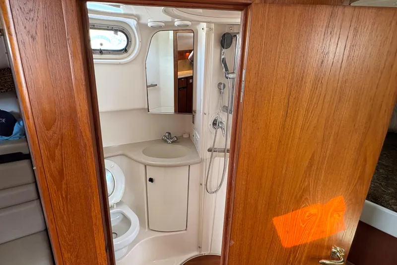 Slide: The Image of 2002 Pursuit 3800 Express yacht bathroom with sink, shower, and wooden door. - 11