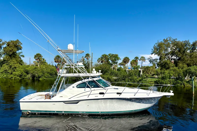 Slide: The Image of 2002 Pursuit 3800 Express boat on calm water with lush greenery background. - 4
