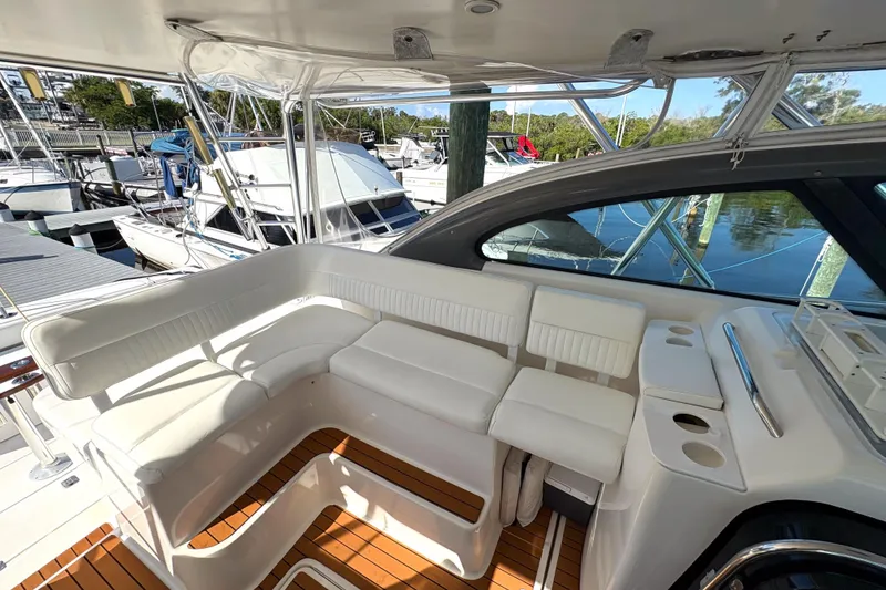 Slide: The Image of 2002 Pursuit 3800 Express yacht interior with white seating and wooden flooring at a marina. - 5