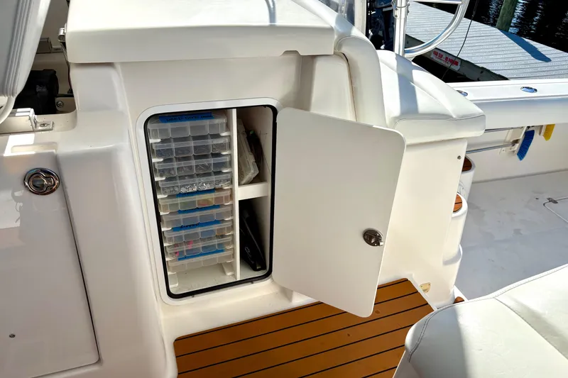Slide: The Image of Open storage compartment on 2002 Pursuit 3800 Express boat with organized tackle boxes. - 7