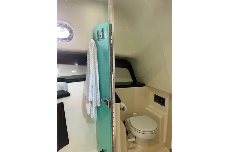 Slide: The Image of 2009 Pursuit OS 375 Offshore bathroom with toilet, towel, and porthole window. - 16