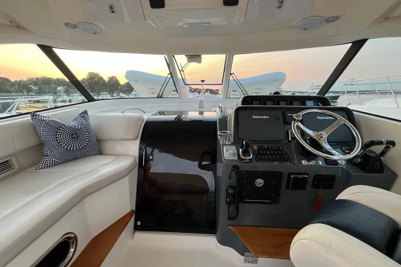 Slide: The Image of 2009 Pursuit OS 375 Offshore helm with luxurious seating and modern controls at sunset. - 4