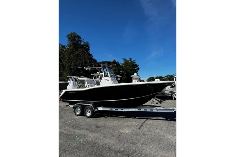 Slide: The Image of 2026 Tidewater 232 CC Adventure boat on trailer under clear blue sky. - 2