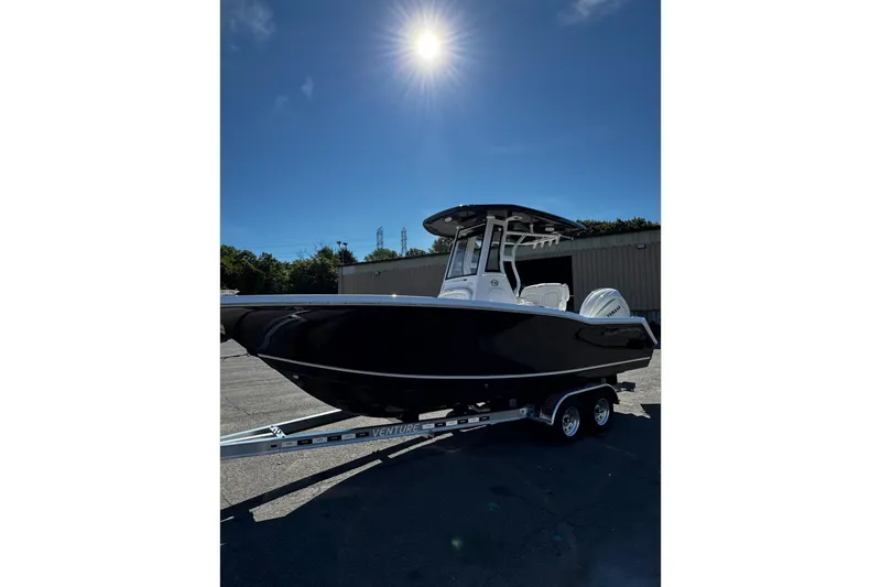 Slide: The Image of 2026 Tidewater 232 CC Adventure boat on trailer under clear blue sky. - 5