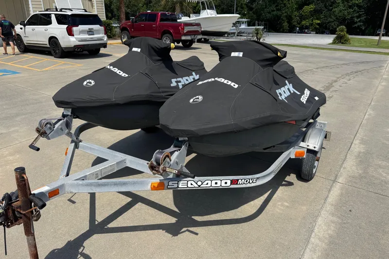 Slide: The Image of 2017 Sea-Doo Spark 2up jet skis on trailer, covered and parked outdoors. - 1