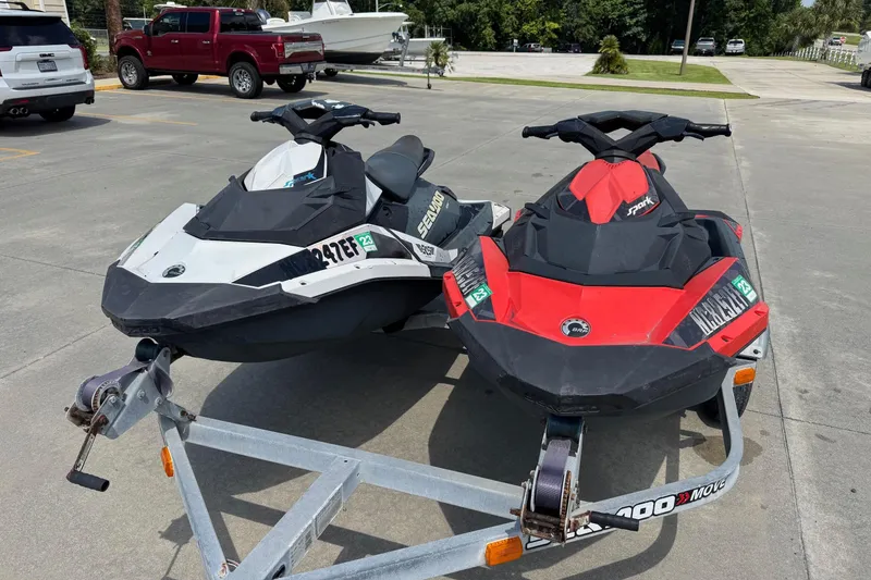 Slide: The Image of Two 2017 Sea-Doo Spark 2up jet skis on a trailer in a parking lot. - 2
