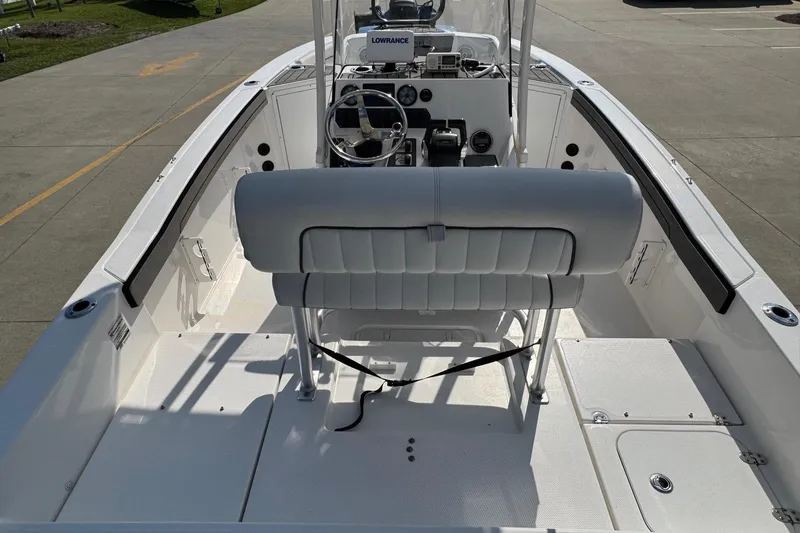 Slide: The Image of 2018 Yamaha Boats 210 FSH interior with steering console and seating, docked on concrete. - 7
