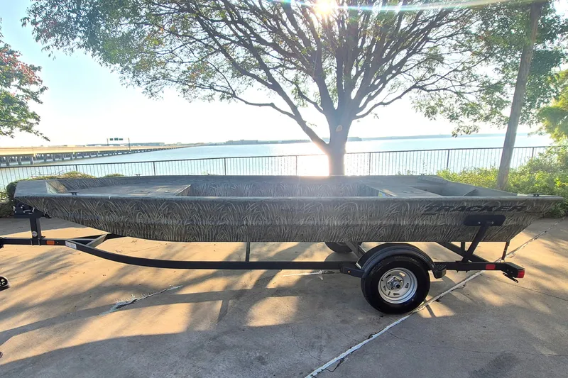 The Image of 2026 Tracker Grizzly 1860 Utility boat on trailer by a lakeside at sunset. - 0