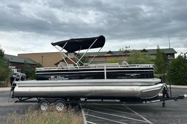 The Image of 2025 Sun Tracker Sportfish 24 XP3 pontoon boat on trailer, parked outdoors. - 0