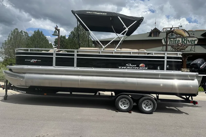 The Image of 2025 Sun Tracker Sportfish 24 XP3 pontoon boat on trailer, parked near White River Fly Shop. - 0