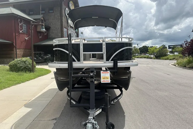 Slide: The Image of 2025 Sun Tracker Sportfish 24 XP3 pontoon boat on trailer, parked outside a building. - 6