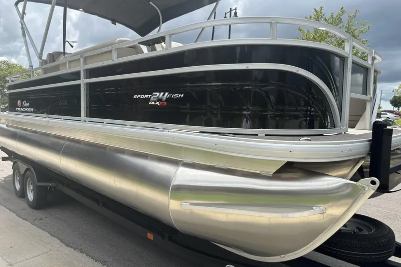 Slide: The Image of 2025 Sun Tracker Sportfish 24 XP3 pontoon boat on trailer, sleek black and silver design. - 5