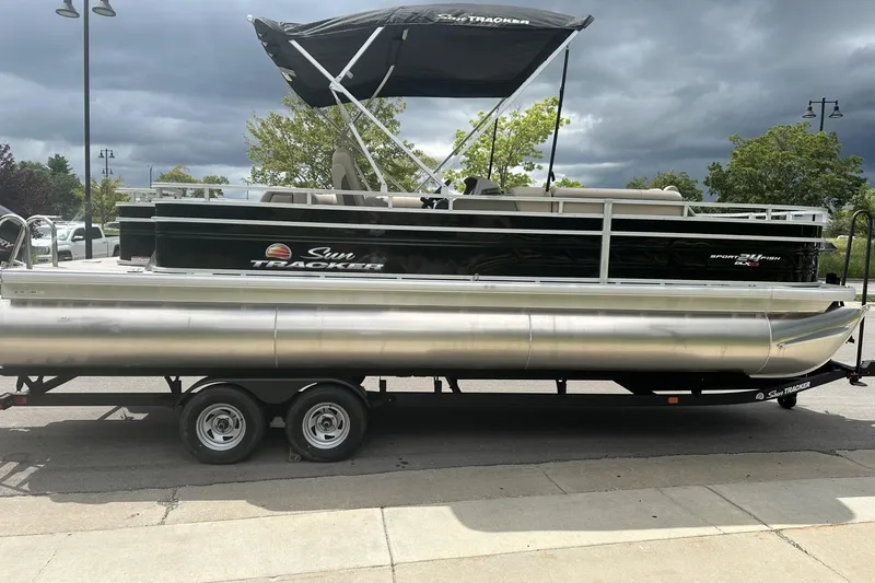 Slide: The Image of 2025 Sun Tracker Sportfish 24 XP3 pontoon boat on trailer, parked outdoors. - 4