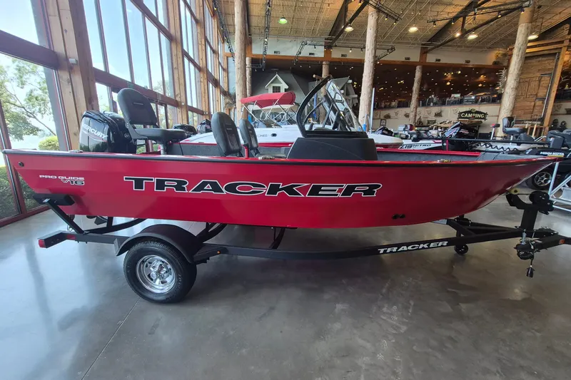 The Image of Red 2026 Tracker Pro Guide V-16 WT boat displayed indoors on a trailer. - 0