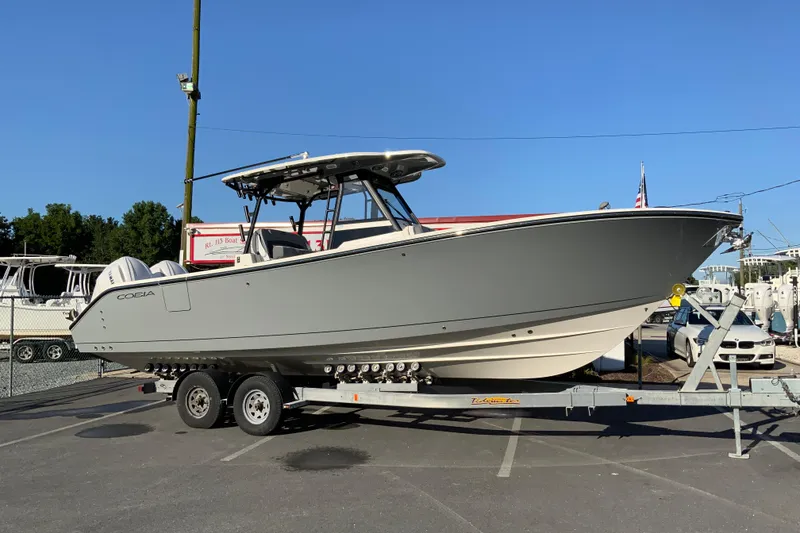 Slide: The Image of 2026 Cobia 305 Center Console boat on trailer in parking lot, clear blue sky. - 1