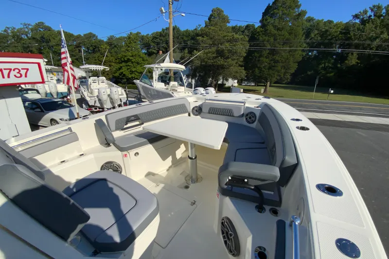 Slide: The Image of 2026 Cobia 305 Center Console boat with seating and table, parked outdoors. - 100