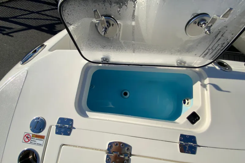 Slide: The Image of Open storage compartment on 2026 Cobia 305 Center Console boat, featuring blue interior. - 20