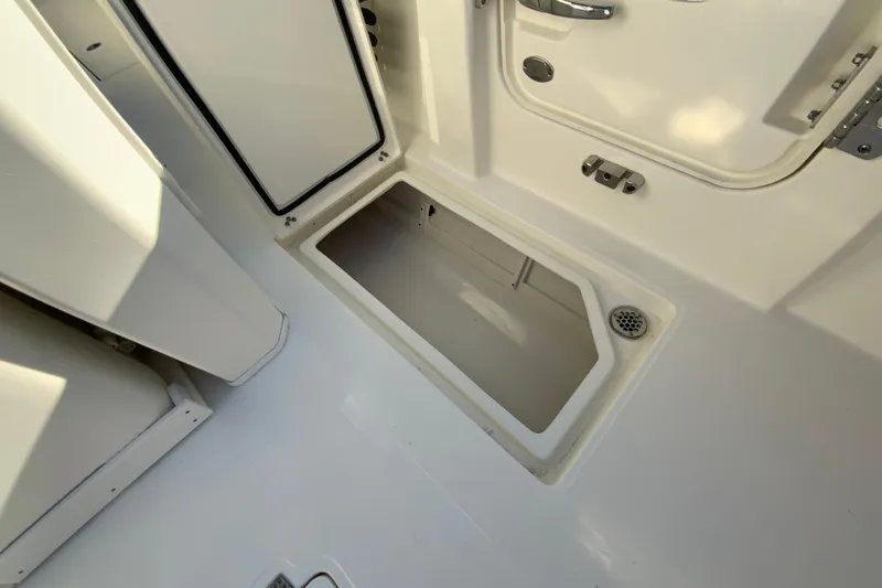 Slide: The Image of 2026 Cobia 305 Center Console storage compartment with open hatch and drain. - 26