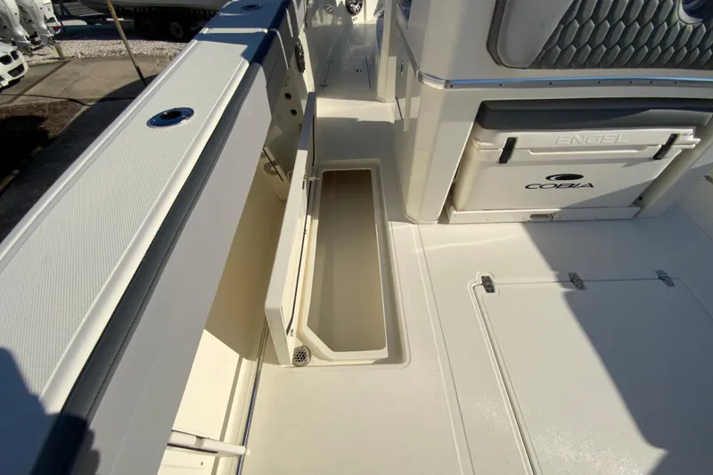 Slide: The Image of 2026 Cobia 305 Center Console boat interior with storage compartments and Engel cooler. - 27